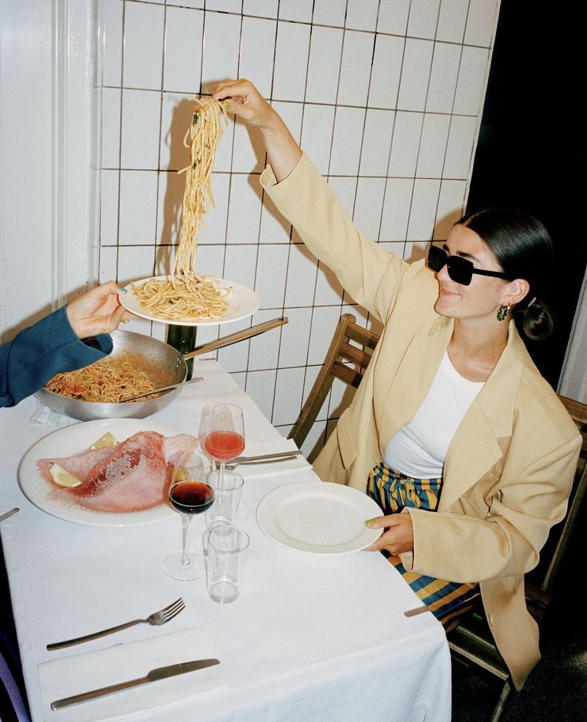 Gościni restauracji podająca makaron przy wspólnym stole